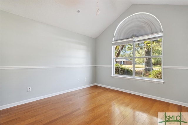 spare room with hardwood / wood-style floors and vaulted ceiling