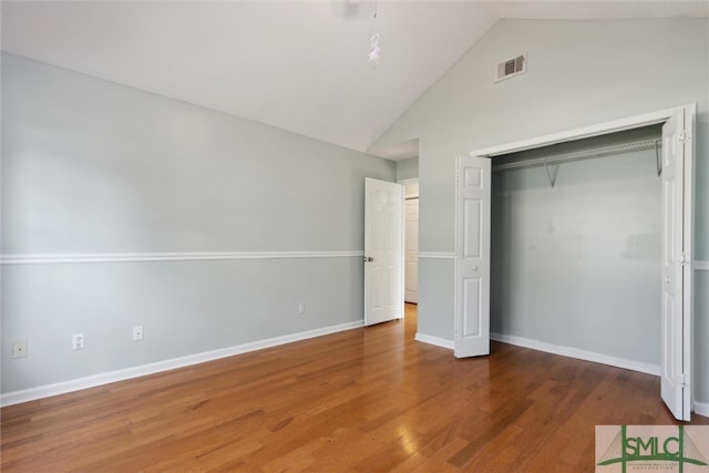 unfurnished bedroom featuring a closet, vaulted ceiling, and hardwood / wood-style floors