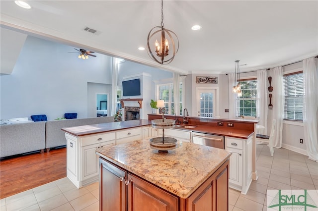 kitchen with white cabinets, stainless steel dishwasher, light tile patterned flooring, decorative light fixtures, and a center island