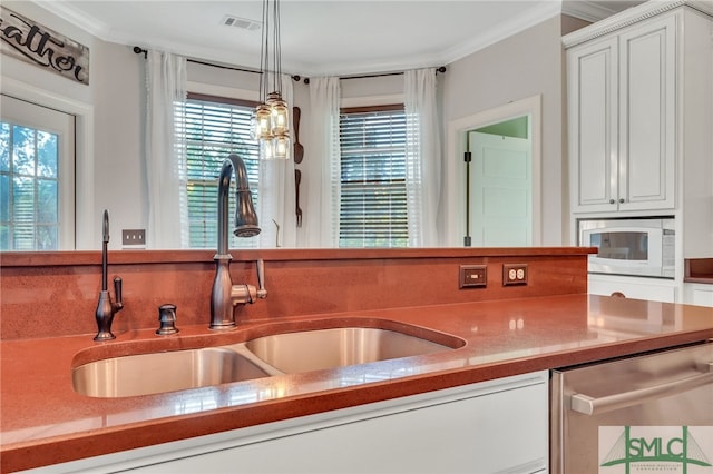 kitchen with white microwave, white cabinetry, pendant lighting, and a healthy amount of sunlight