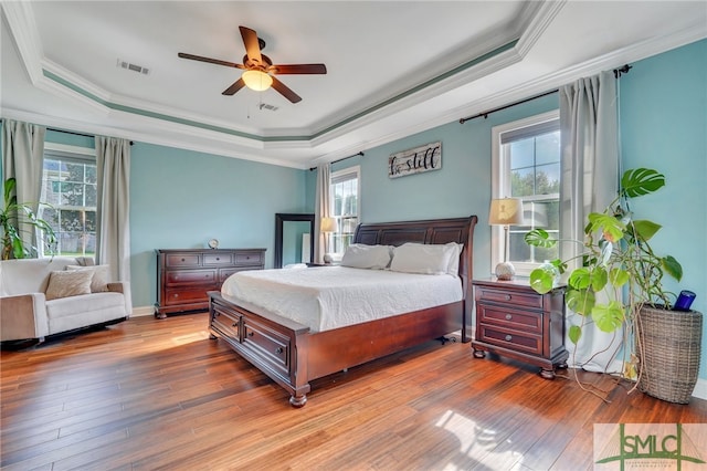 bedroom featuring ceiling fan, a tray ceiling, and dark hardwood / wood-style flooring