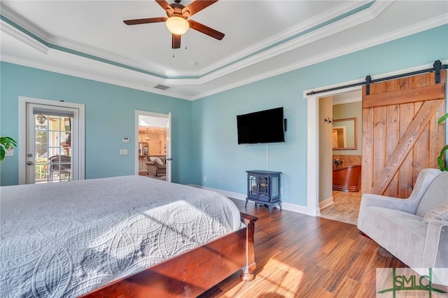 bedroom with hardwood / wood-style floors, connected bathroom, a raised ceiling, and ceiling fan