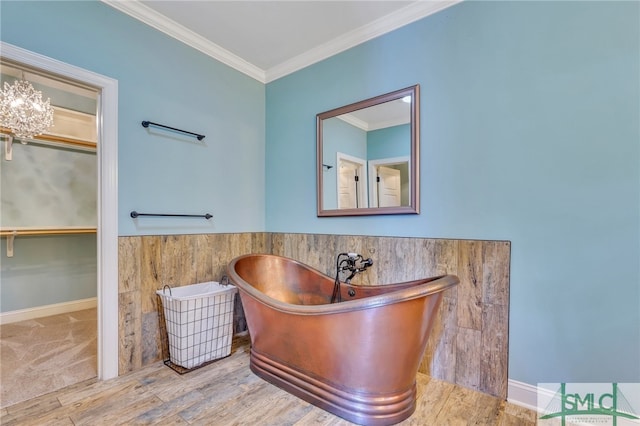 bathroom featuring ornamental molding, an inviting chandelier, a tub, and hardwood / wood-style flooring