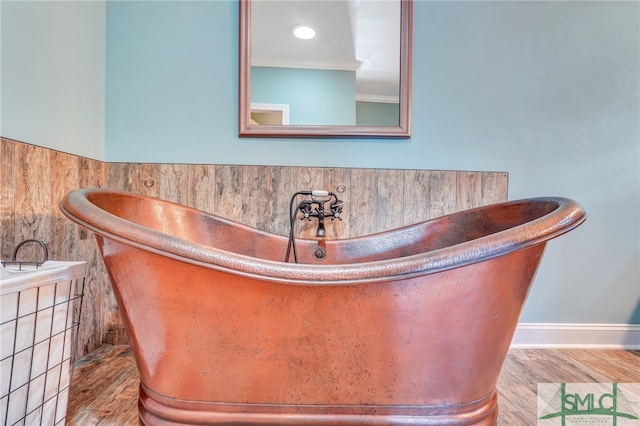 bathroom featuring ornamental molding, a bathtub, and wood-type flooring