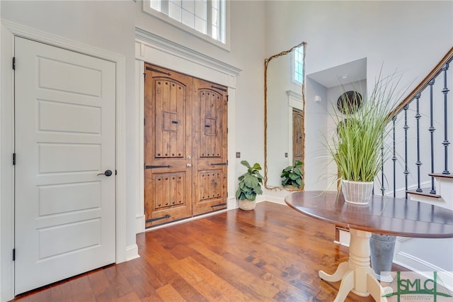 foyer entrance with wood-type flooring and a towering ceiling