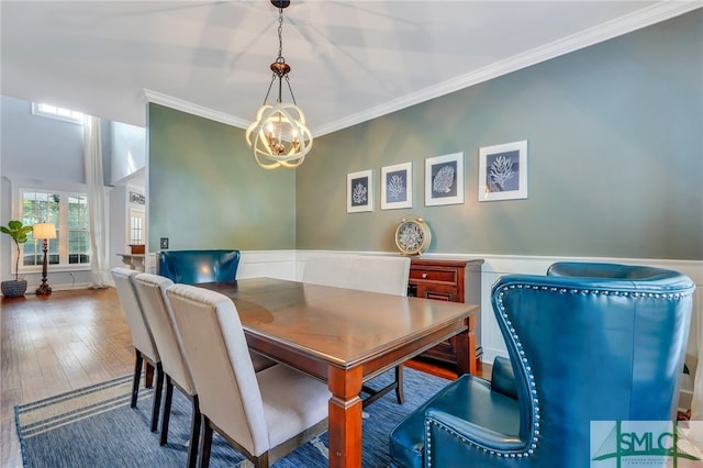 dining space with ornamental molding, hardwood / wood-style flooring, and an inviting chandelier