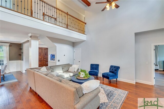 living room featuring a towering ceiling, crown molding, hardwood / wood-style flooring, and ceiling fan