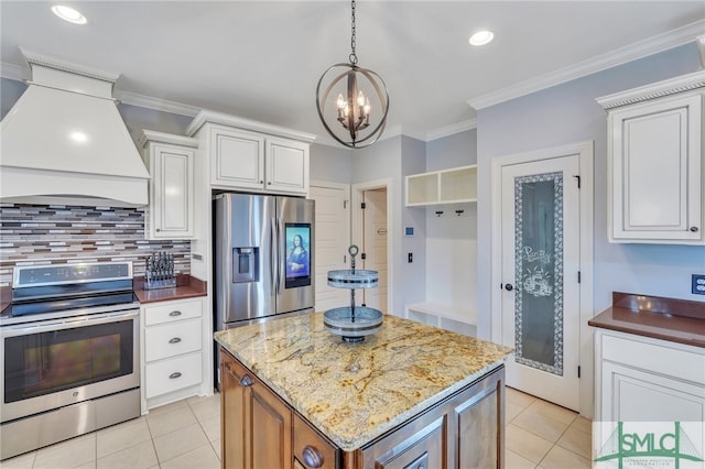 kitchen with appliances with stainless steel finishes, a kitchen island, white cabinetry, ornamental molding, and premium range hood