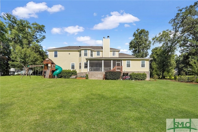 rear view of property with a playground, a yard, and a sunroom