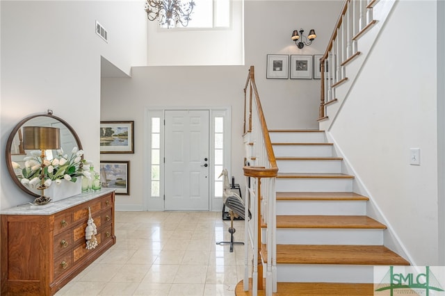 foyer entrance with a notable chandelier, a towering ceiling, and a wealth of natural light