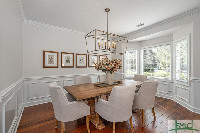 dining area with ornamental molding, dark wood-type flooring, and a notable chandelier