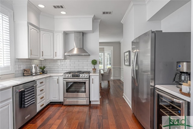 kitchen with dark hardwood / wood-style flooring, stainless steel appliances, white cabinetry, and wall chimney range hood