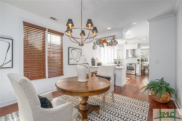 dining area featuring ceiling fan with notable chandelier, crown molding, and dark wood-type flooring