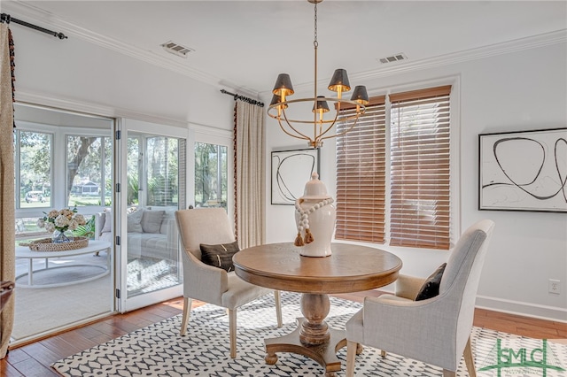 dining space featuring crown molding, a chandelier, and light wood-type flooring