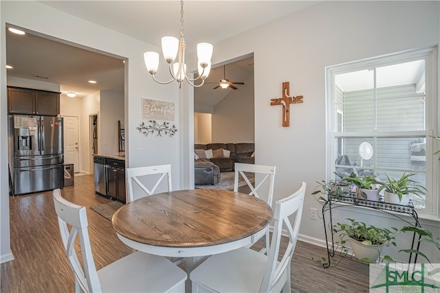 dining space with dark wood-type flooring and ceiling fan with notable chandelier