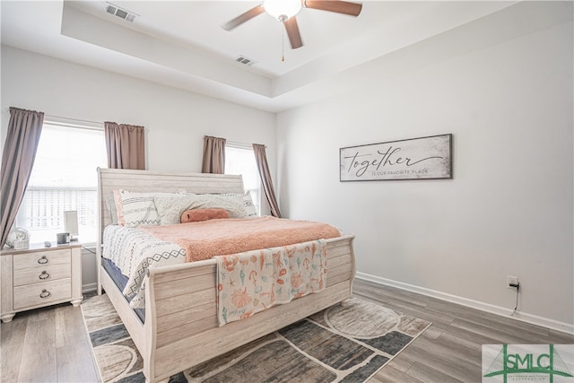 bedroom with multiple windows, dark hardwood / wood-style floors, and ceiling fan