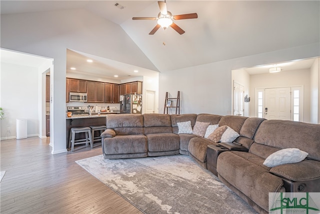 living room featuring dark hardwood / wood-style floors, high vaulted ceiling, and ceiling fan