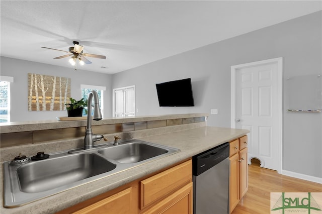 kitchen with a healthy amount of sunlight, stainless steel dishwasher, sink, and light wood-type flooring