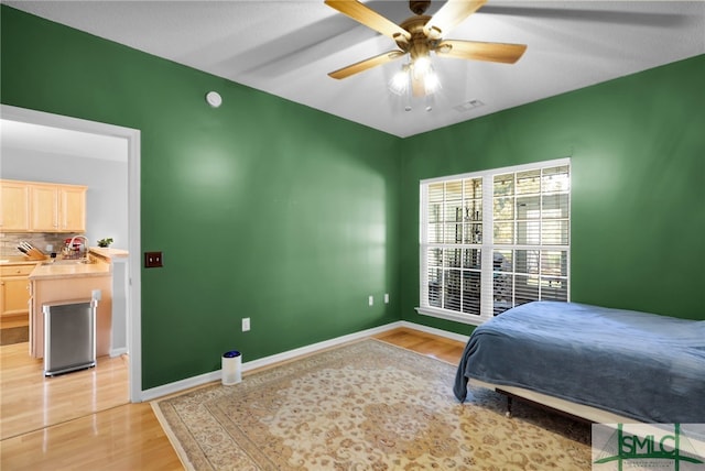 bedroom featuring ceiling fan, sink, and light wood-type flooring