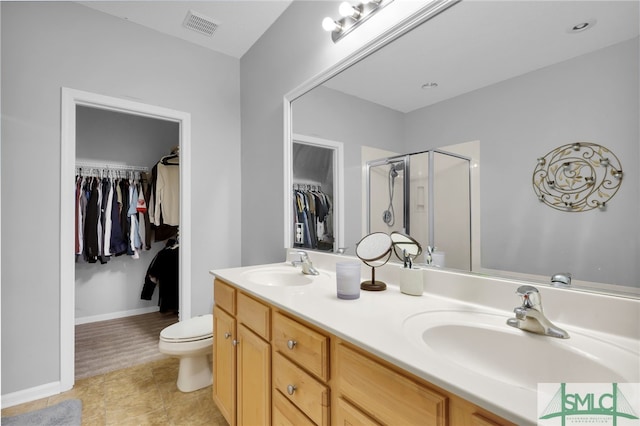 bathroom with a shower with door, vanity, toilet, and tile patterned floors