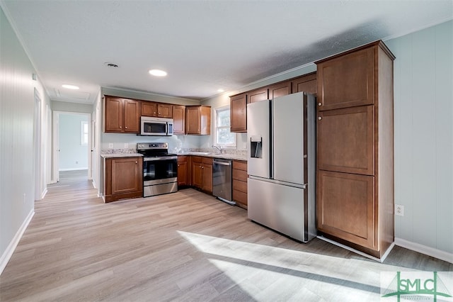 kitchen featuring stainless steel appliances, ornamental molding, sink, and light wood-type flooring