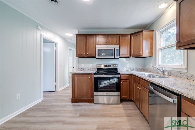 kitchen with sink, crown molding, stainless steel appliances, and light wood-type flooring