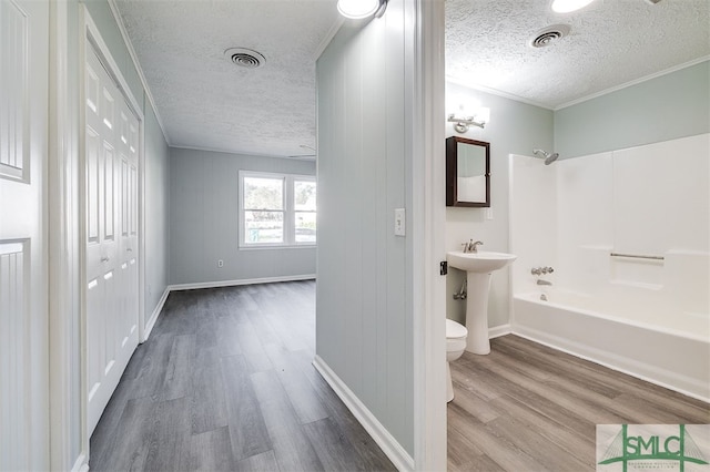 bathroom featuring toilet, a textured ceiling, wood-type flooring, and shower / tub combination