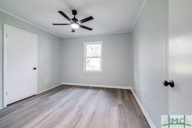 empty room featuring ornamental molding, light wood-type flooring, and ceiling fan