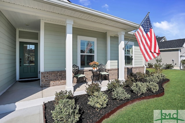 view of exterior entry with a yard and covered porch