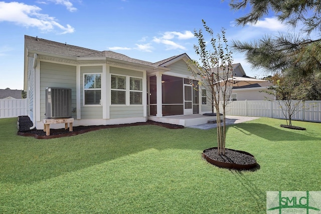 rear view of house with a sunroom, a lawn, and a patio area