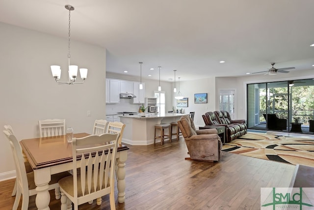 dining area with ceiling fan with notable chandelier and light wood-type flooring