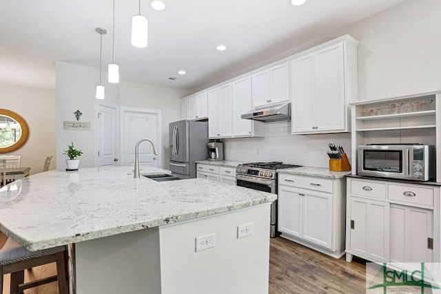 kitchen with appliances with stainless steel finishes, sink, white cabinetry, pendant lighting, and a center island with sink