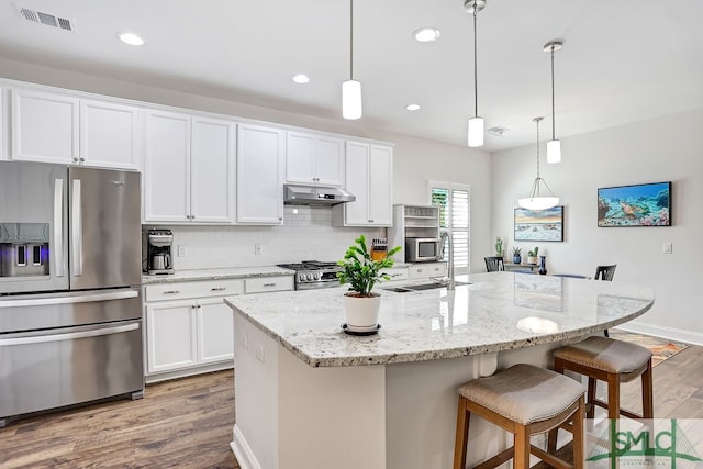 kitchen featuring an island with sink, stainless steel appliances, white cabinets, and light hardwood / wood-style floors