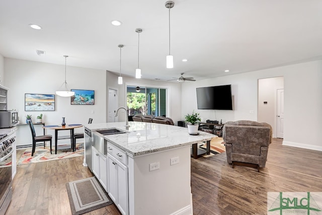 kitchen with light stone counters, dark hardwood / wood-style flooring, white cabinetry, a kitchen island with sink, and sink