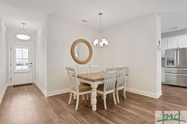 dining space featuring wood-type flooring and an inviting chandelier