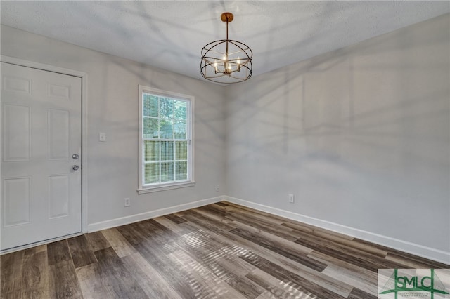 interior space featuring a notable chandelier, dark hardwood / wood-style floors, and a textured ceiling