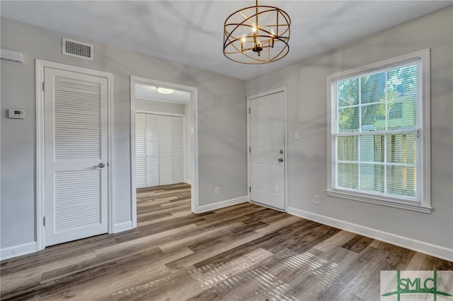 entryway with an inviting chandelier, hardwood / wood-style floors, and a textured ceiling