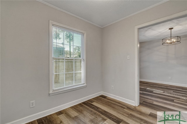 spare room featuring ornamental molding, a textured ceiling, hardwood / wood-style flooring, and a chandelier