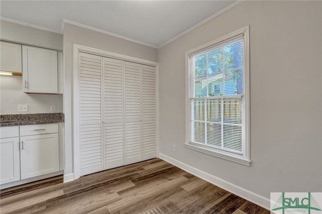 unfurnished dining area featuring ornamental molding, a textured ceiling, and wood-type flooring