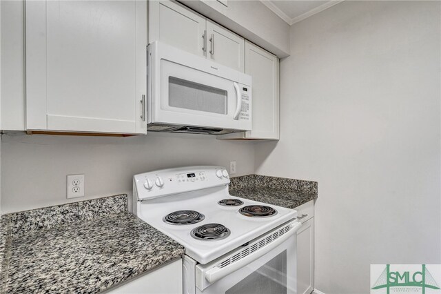 kitchen featuring crown molding, white cabinetry, dark stone counters, and white appliances