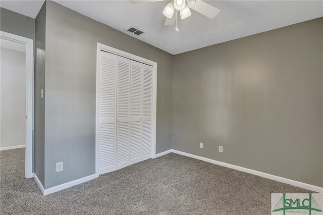 unfurnished bedroom featuring a closet, ceiling fan, a textured ceiling, and carpet floors