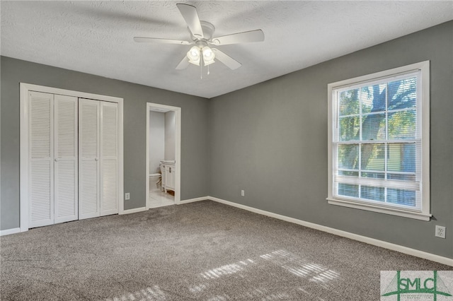 unfurnished bedroom with a textured ceiling, a closet, ceiling fan, light carpet, and connected bathroom