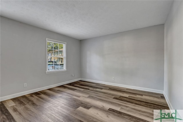 spare room with a textured ceiling and hardwood / wood-style flooring