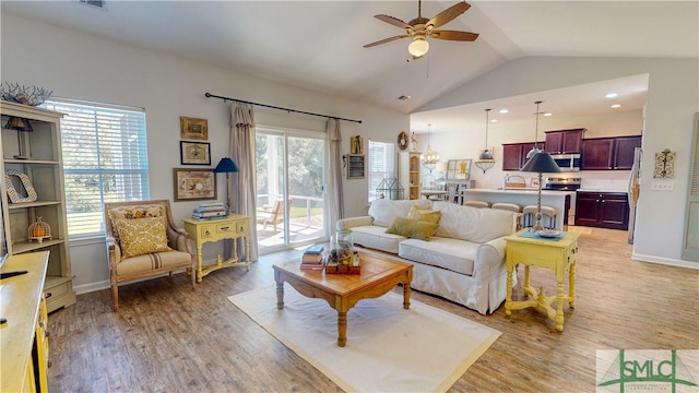 living room with ceiling fan, a healthy amount of sunlight, lofted ceiling, and light hardwood / wood-style flooring