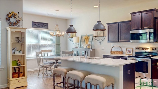 kitchen with sink, pendant lighting, a breakfast bar, a center island with sink, and appliances with stainless steel finishes