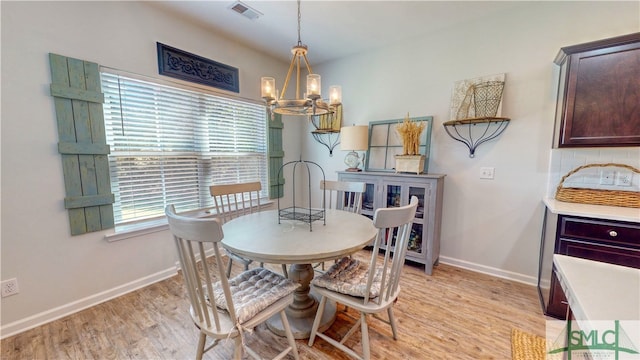 dining room with light hardwood / wood-style flooring and an inviting chandelier