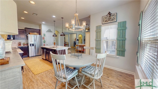 dining area with an inviting chandelier, light hardwood / wood-style flooring, and sink