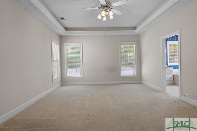 unfurnished room featuring ceiling fan, light carpet, a raised ceiling, baseboards, and visible vents
