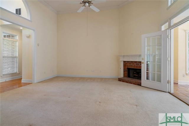 unfurnished living room featuring a towering ceiling, visible vents, a ceiling fan, ornamental molding, and carpet floors