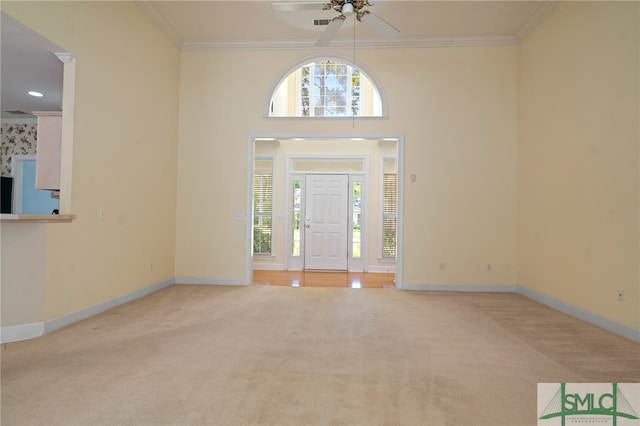 foyer entrance featuring crown molding, light colored carpet, and ceiling fan